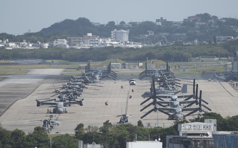 A distant overhead view of a military runway with several Osprey titltrotor aircraft parked in two parallel lines.