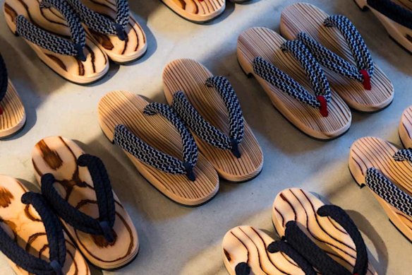 Rows of geta, traditional Japanese sandal-like footwear with flat wooden bases, are lined outside premises in Ozu.