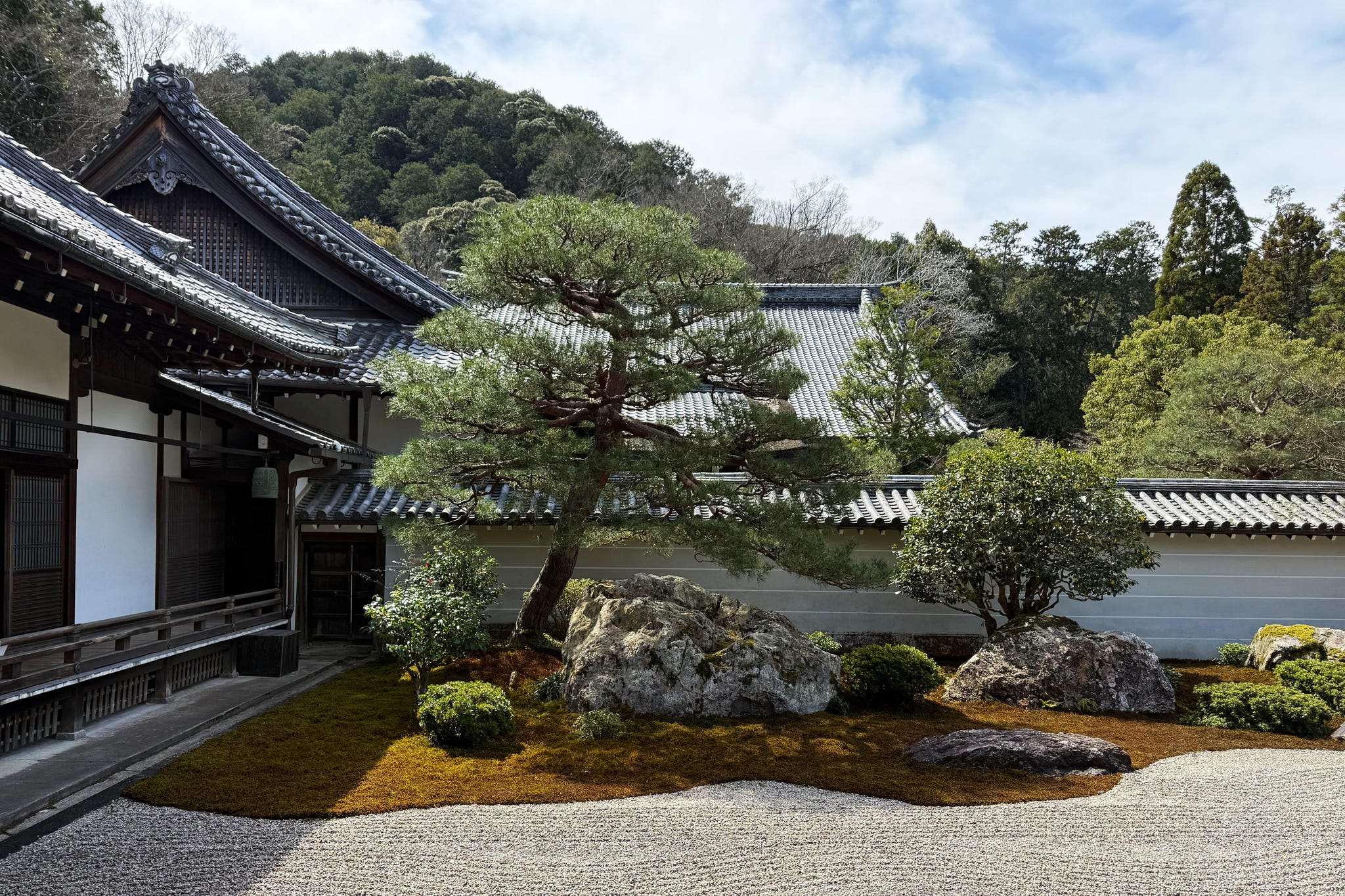 Zen garden featuring rocks, plants, and traditional architecture.