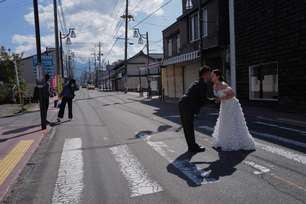 Foreign visitors pose for photos at Honcho Street with Mt. Fuji as background.