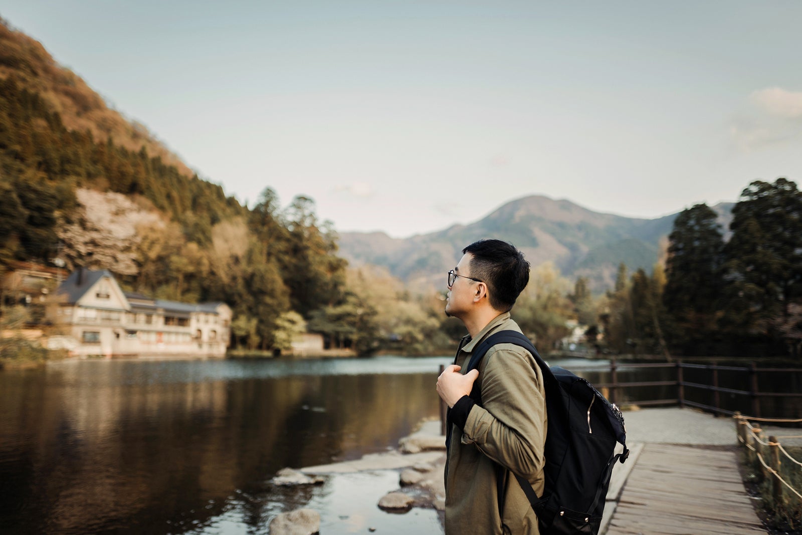Young man with backpack sightseeing at lake relaxing and enjoying the beautiful scene