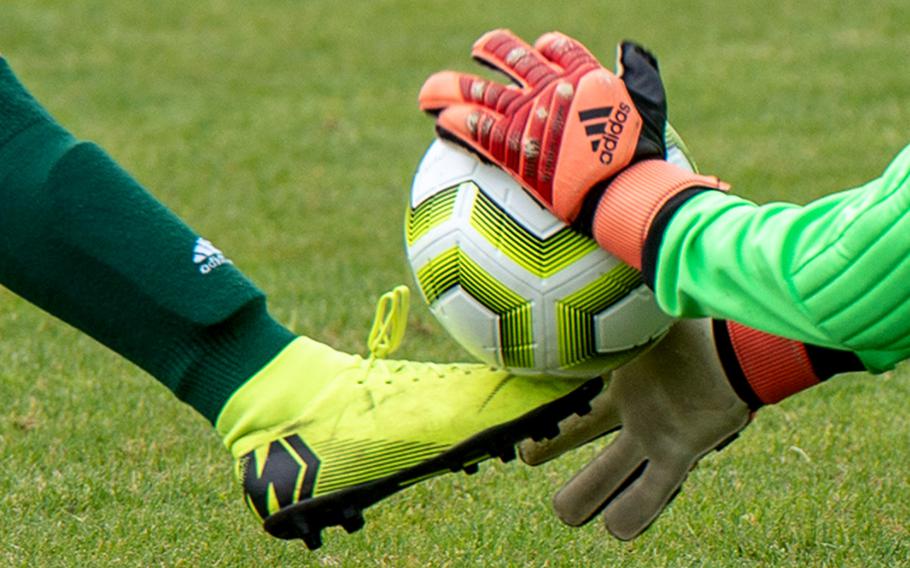 A boot and hand meet at the soccer ball.