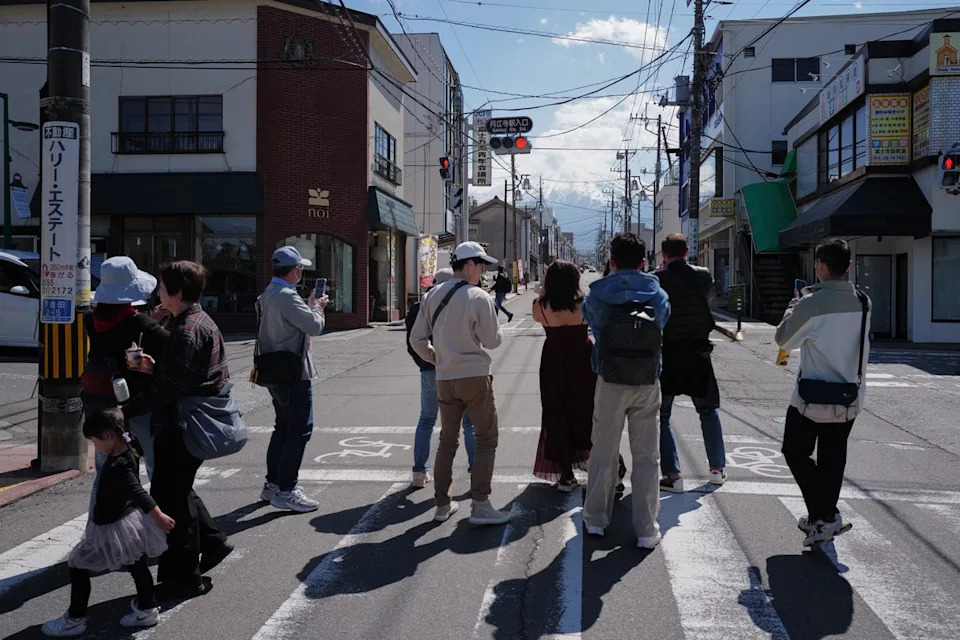 Tourists stand in the street to take photos of Mount Fuji (AP)