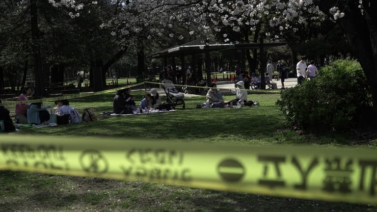 People sit down for a picnic outside a cordoned-off area...