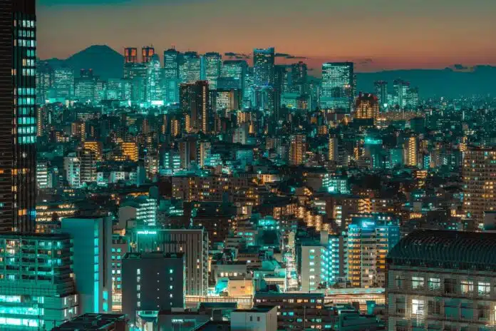 A sprawling cityscape of Tokyo at dusk, with Mount Fuji visible in the distance.