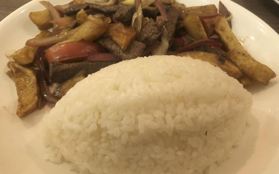 Meat and vegetables on a plate next to a mound of rice.