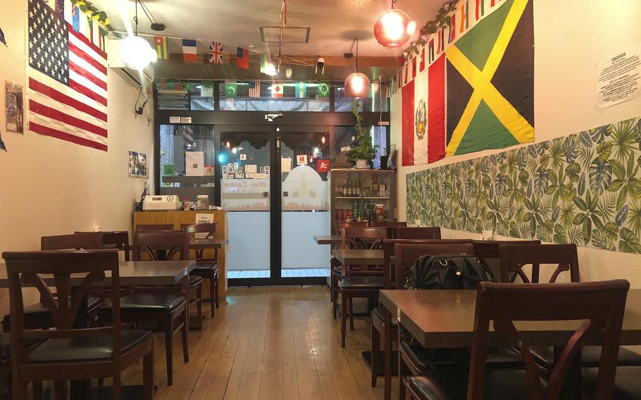 A restaurant interior has wooden tables and chairs, and flags on the walls.