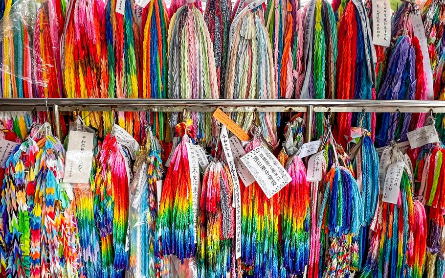 Racks of strings of colorful folded paper cranes are displayed.