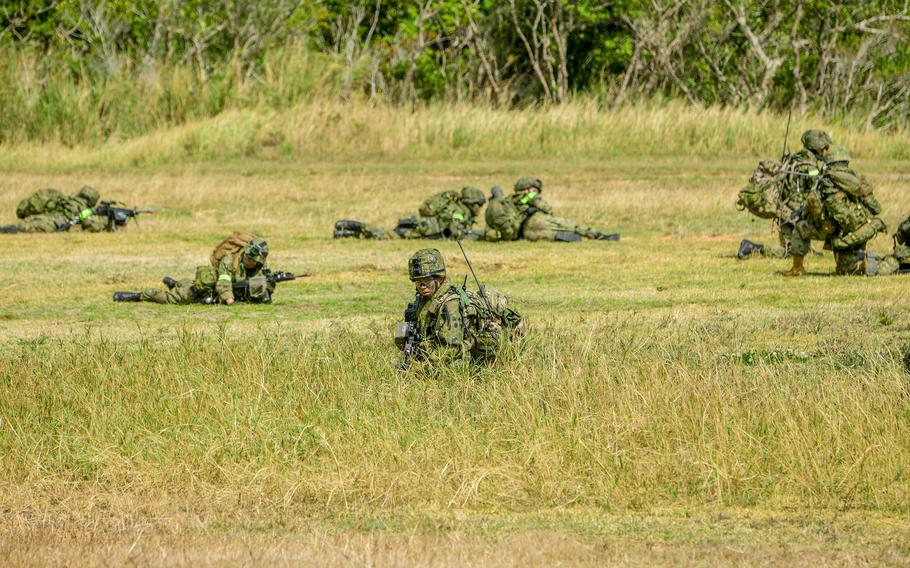 Military soldiers move through an open field.
