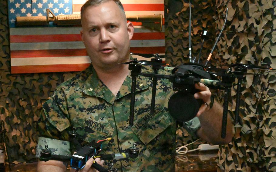 A major holds a seven-inch training drone in his right hand.