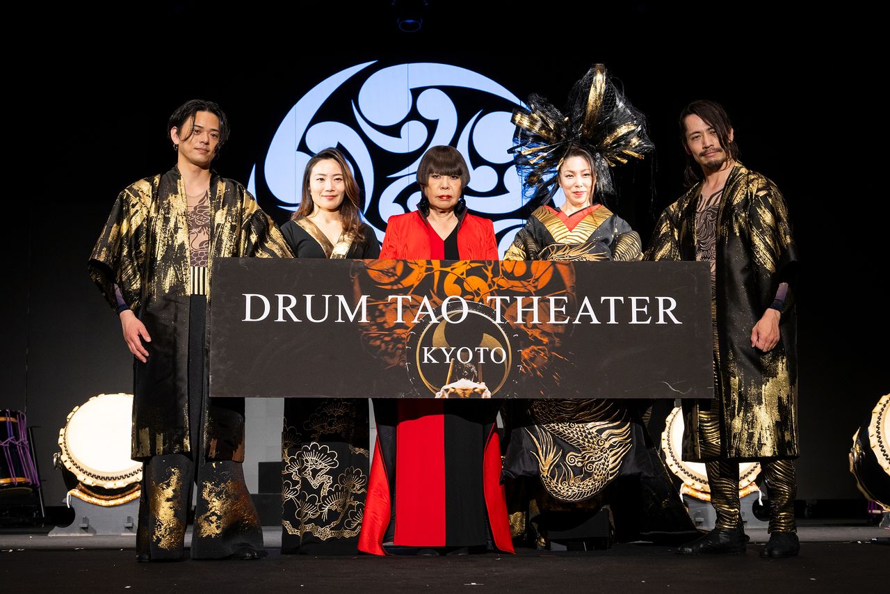 Koshino Junko flanked by Drum Tao performers in her eye-catching designs. (© Nippon.com)