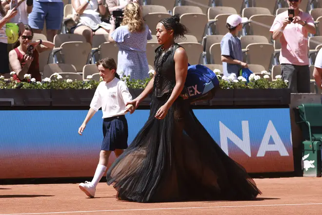 Naomi Osaka of Japan enters the court wearing a custom Nike black dress ahead of her first round match against Laura Siegemund