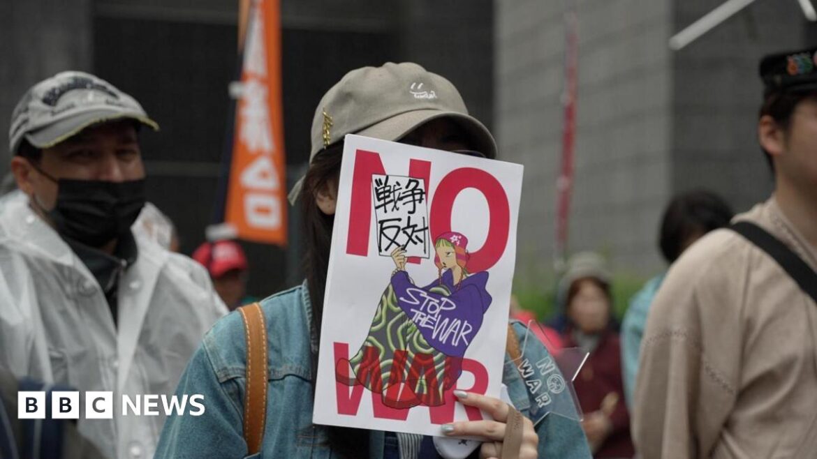 Anti-war protests rock Japan as PM Sanae Takaichi pushes for stronger defence A person holds a sign over their face with the words 'NO WAR'