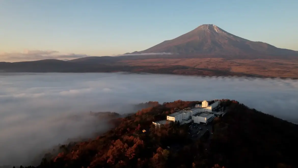 Aerial view of Hotel Mount Fuji overlooking a sea of clouds with Mount Fuji rising in the background in Japan.