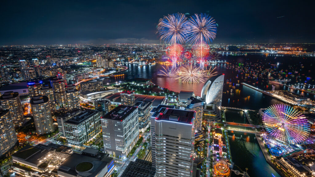 Fireworks over Minato Mirai in Yokohama, with the lit Ferris wheel and waterfront skyline below
