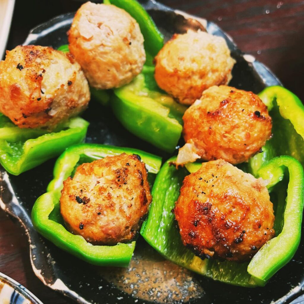 NAMA-P-TSUKUNE is an izakaya dish consisting of meatballs topped with raw bell peppers.