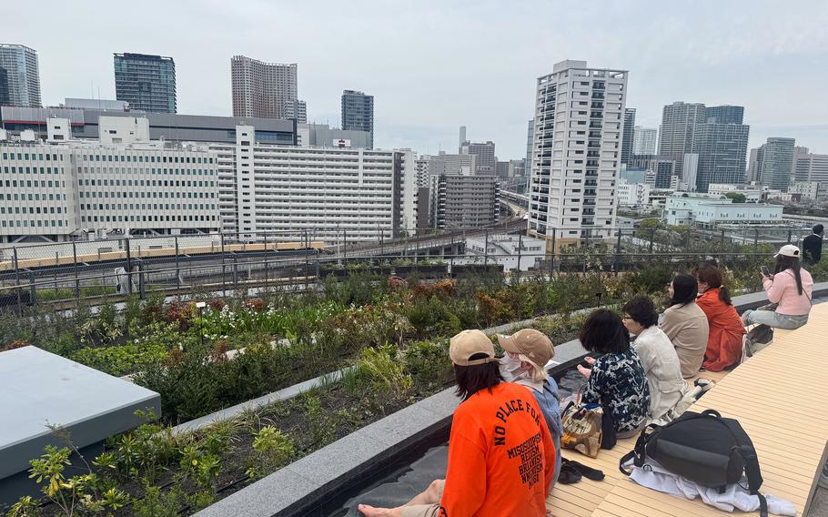 A line of people bathe their feet in a water trough overlooking the city.