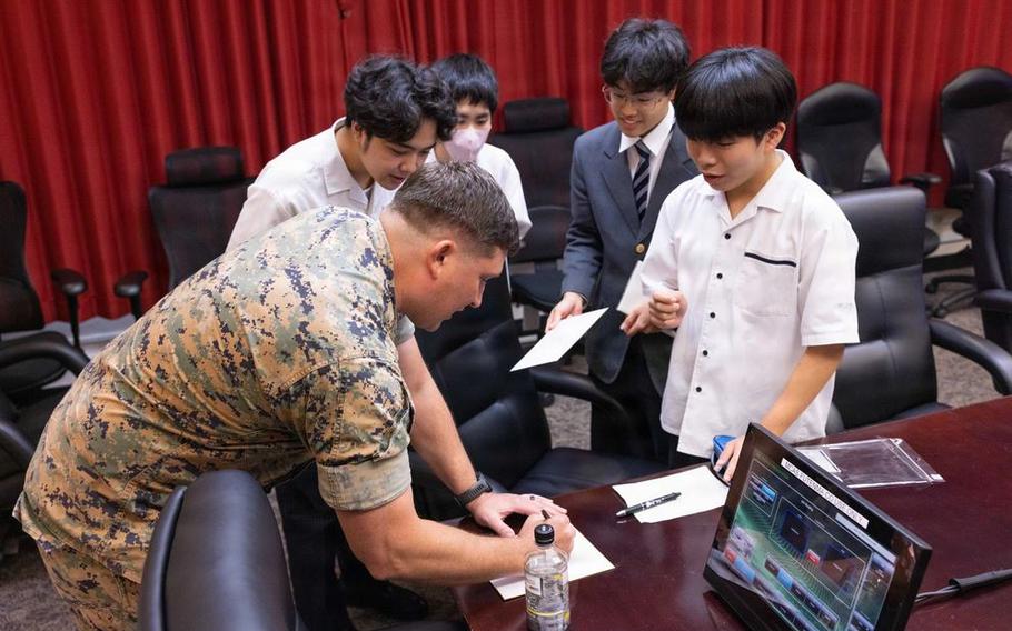 U.S. Marine Corps Maj. Nicholas Rhea, a flight officer with Marine Corps Air Station Futenma, signs an autograph for local high school students at MCAS Futenma, Okinawa, Japan, June 11, 2026.