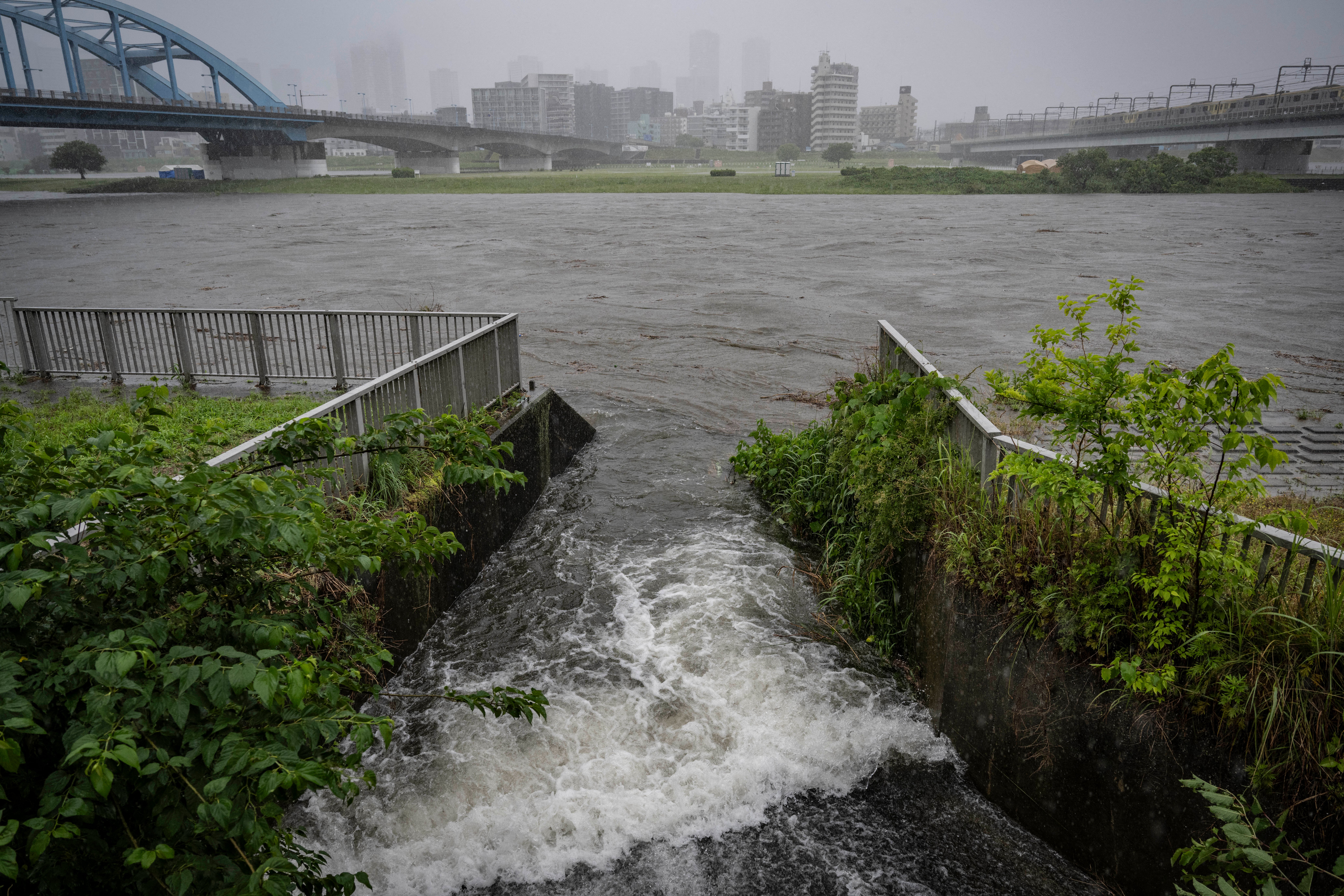 Water flows into the swollen Tama river amid heavy rain brought by severe tropical storm Jangmi in Tokyo on 3 June 2026
