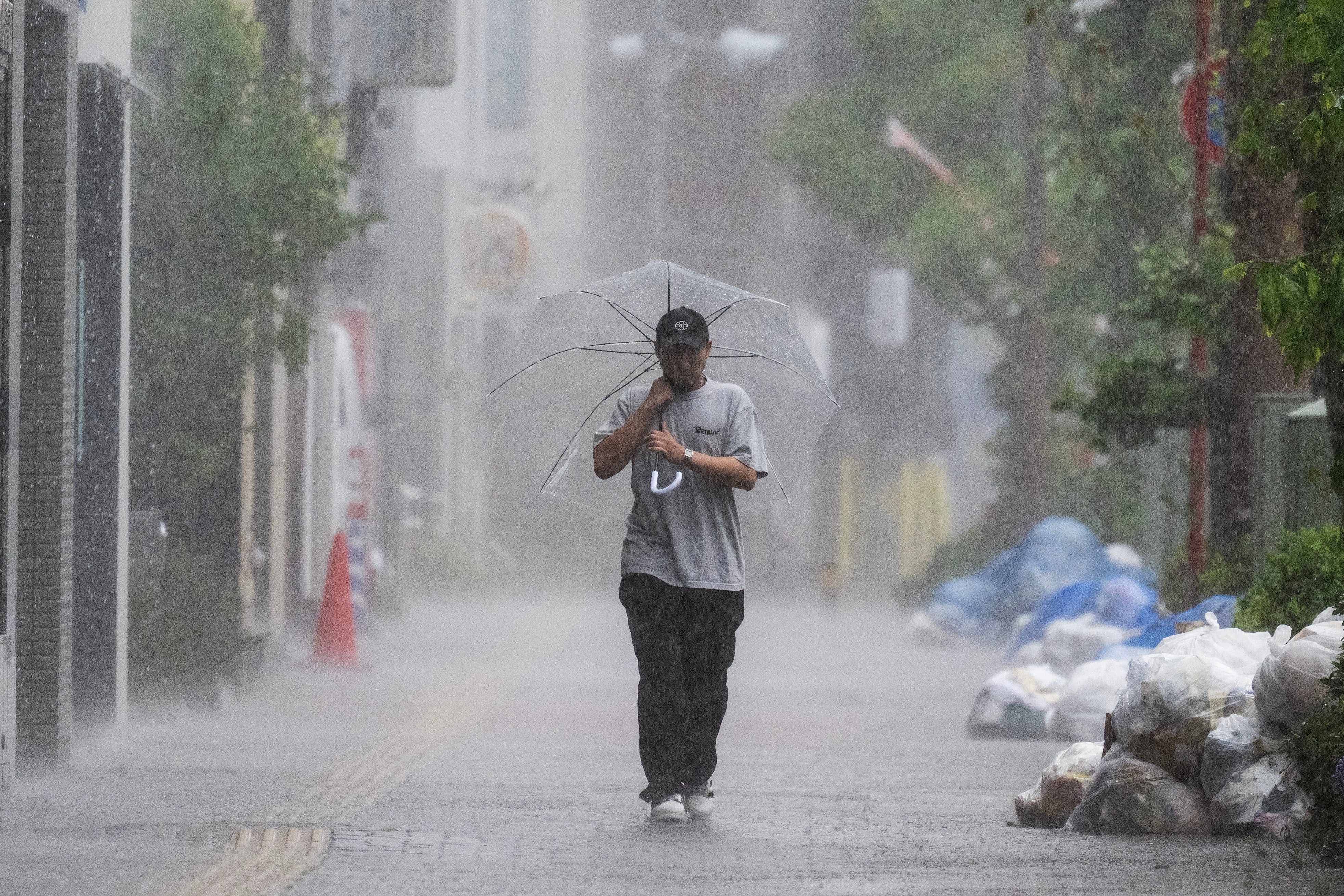 A man walks down a sidewalk in heavy rain brought by severe tropical storm Jangmi in Tokyo on 3 June 2026