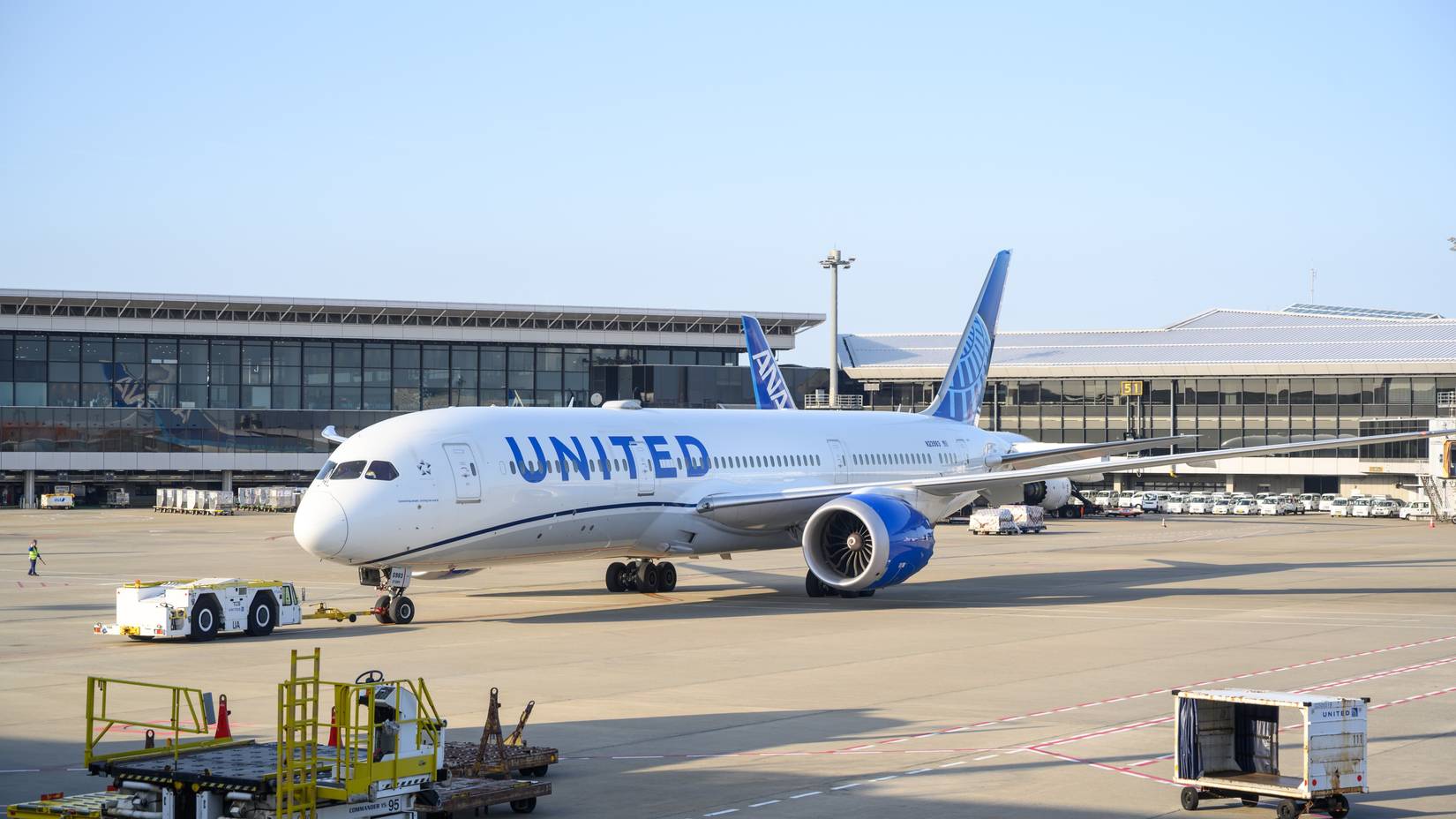 United Airlines aircraft being serviced, parked at the passenger gate at an airport in Tokyo, Japan