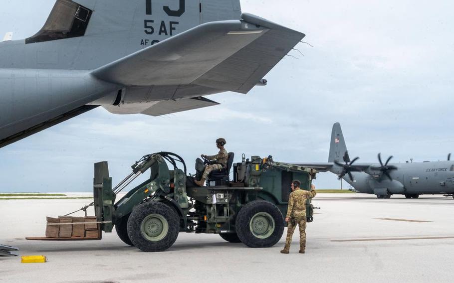 U.S. Air Force personnel load cargo onto a C-130 Hercules on a flight line as another C-130 sits in the background.