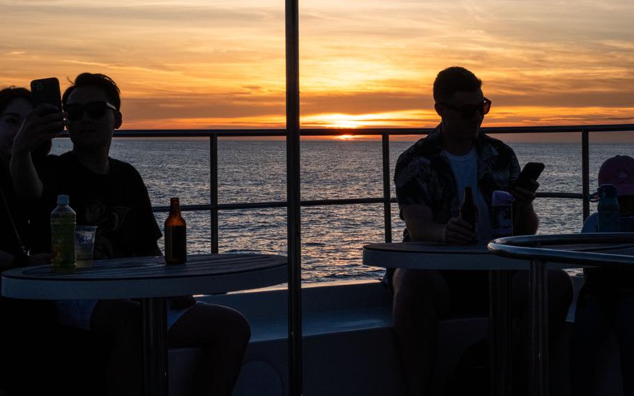 People enjoying sunset cruise on board; taking a selfie and chatting.