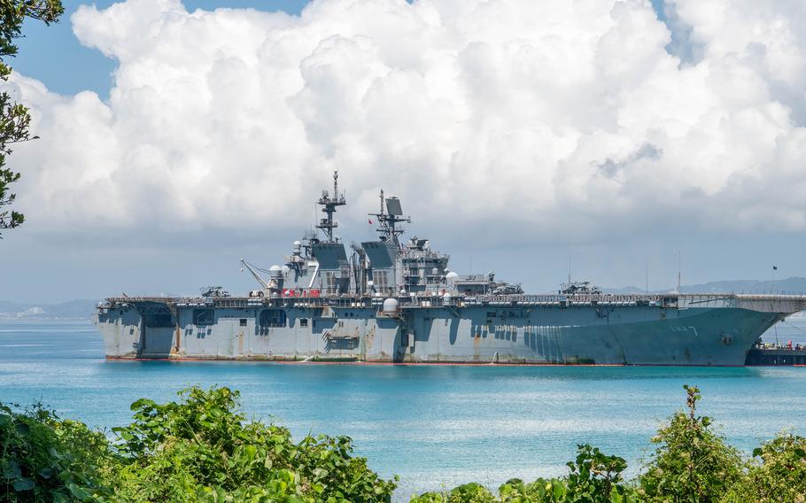 USS Tripoli sails on bright blue water with fluffy white clouds in the background.