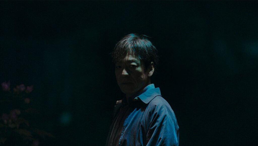 Japan Cuts 2026 — Sheep in the Box, Sai: Disaster, Tokyo Taxi Middle-aged man gazes toward the camera in dark, moody teal-toned lighting.
