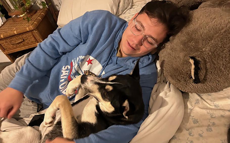 A Marine laying in a bed with his dog.