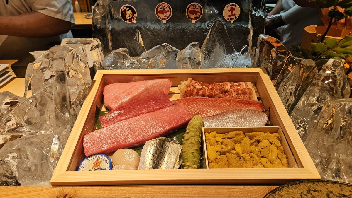 Slabs of fish and containers of row rest in a bamboo box sunk into ice shaped like mountains
