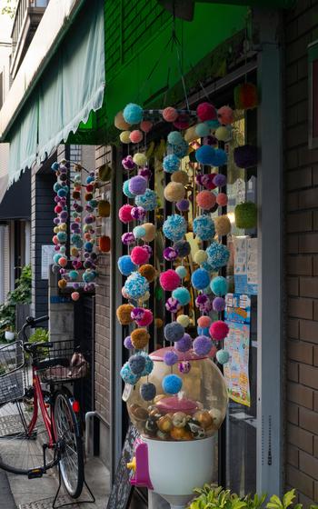 A capsule toy machine and a bike lie in front of a shop in Yanaka Ginza shopping mall.