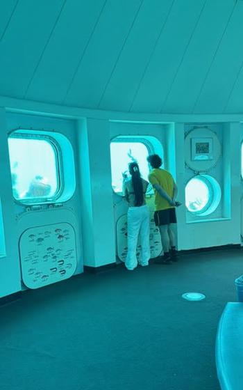 A couple looking at the seas from the window of underwater observatory.